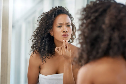 Women looking in the mirror asking what the difference between PCOS and PCO is?
